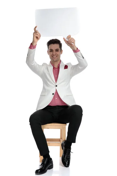 Smiling modern businessman holding speech bubble up in the air — Stock Photo, Image