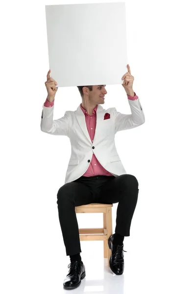 Homem segurando placa em branco no ar olha para o lado — Fotografia de Stock