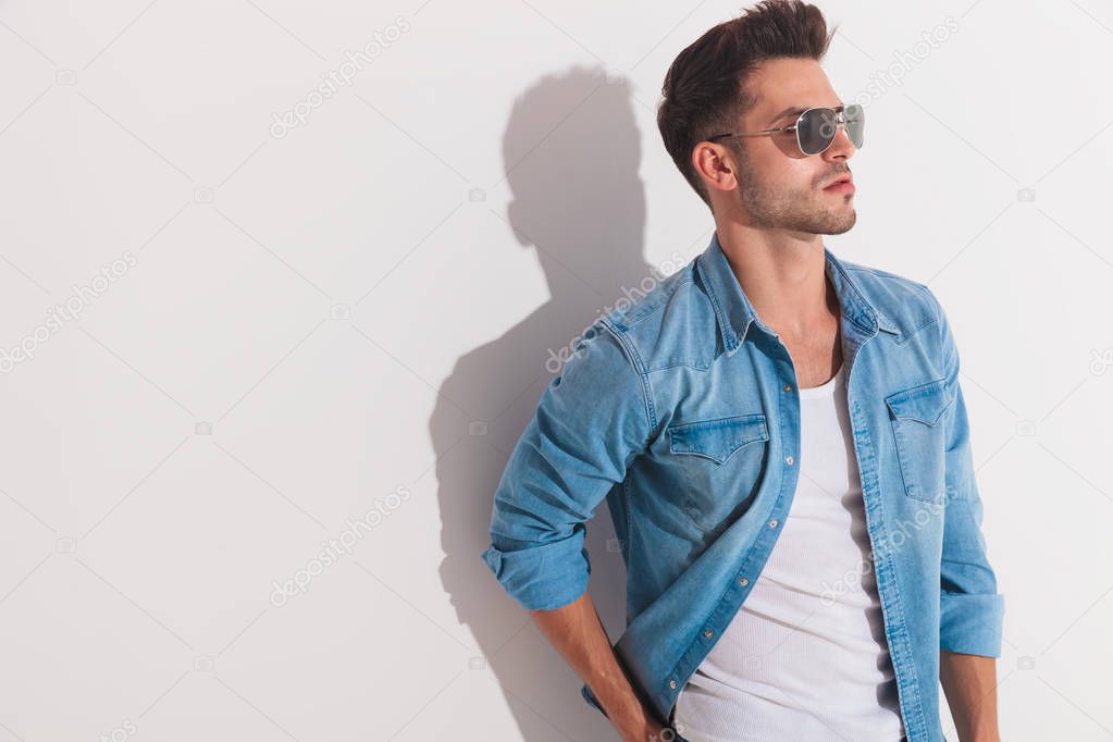 Attractive man standing against the wall and looking at a side