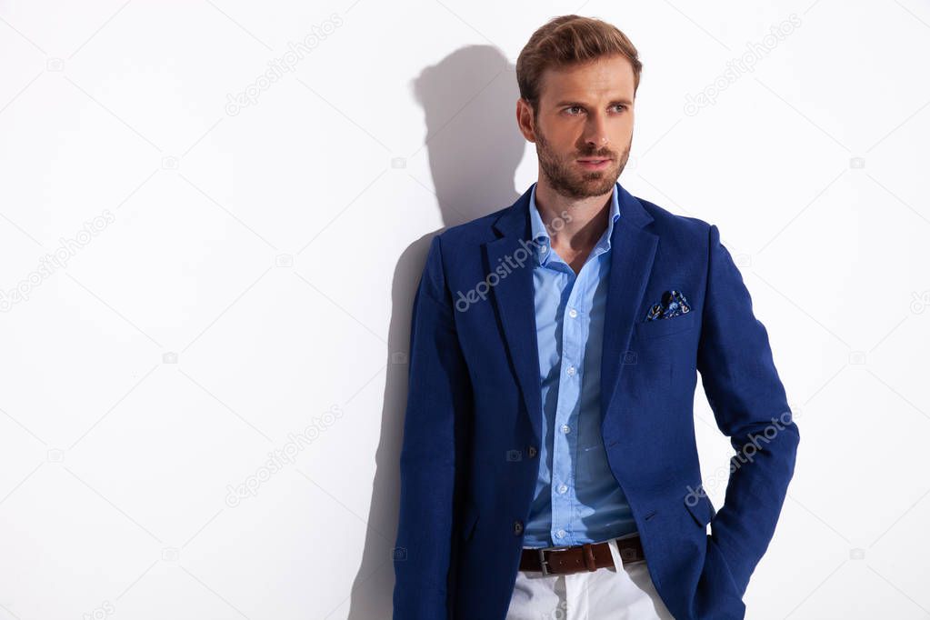 attractive man stands with hand in his pocket and looks away