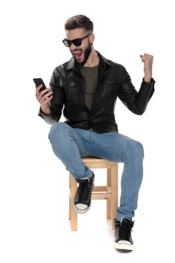 telefon kutluyor bakarken sandalyede oturan adam