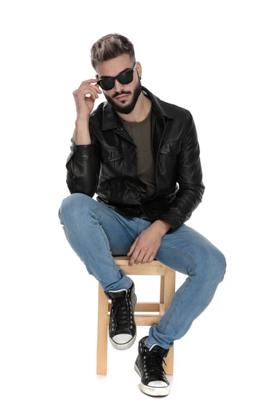 Man in black jacket and blue jeans fixing his sunglasses — Stock Photo, Image