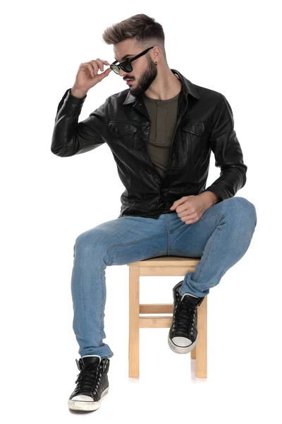Человек в черной куртке и синих джинсах чинит очки — стоковое фото