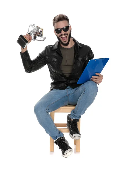 Uomo seduto sulla sedia in possesso di trofeo e cartella blu — Foto Stock