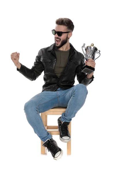 Ο άνθρωπος που κάθεται σε καρέκλα ουρλιάζοντας με Κύπελλο τρόπαιο στο χέρι — Φωτογραφία Αρχείου
