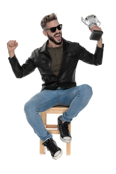 man celebrating victory with a trophy cup in his hand