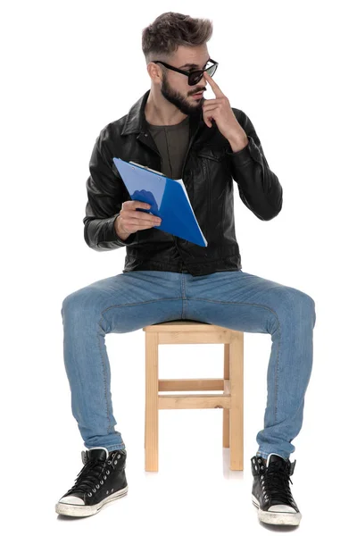 Mann mit blauer Mappe in der Hand justiert seine Sonnenbrille — Stockfoto