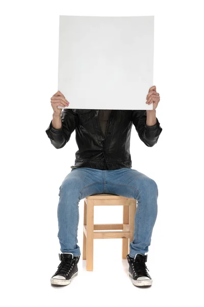 Hombre sosteniendo la cartelera en blanco en la mano mientras cubre su cara — Foto de Stock