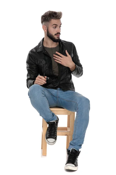 Mężczyzna siedzi na krześle i dziwić się ręką na klatce piersiowej — Zdjęcie stockowe