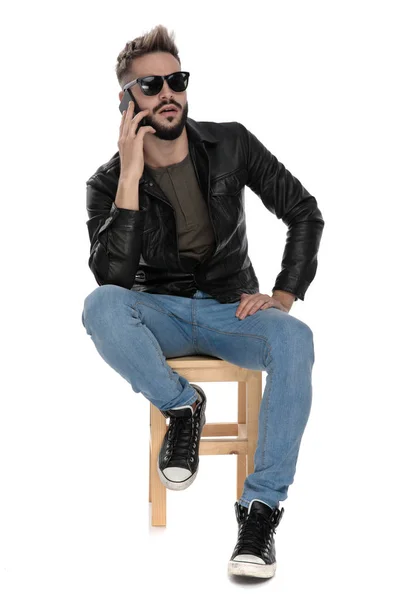 Чоловік сидить на стільці, розмовляючи по телефону, здивований — стокове фото