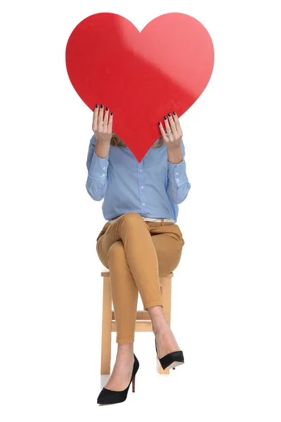 Sentado inteligente casual mulher detém grande amor coração — Fotografia de Stock