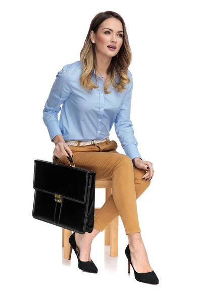 Smart casual vrouw met haar koffer zittend op een woode — Stockfoto