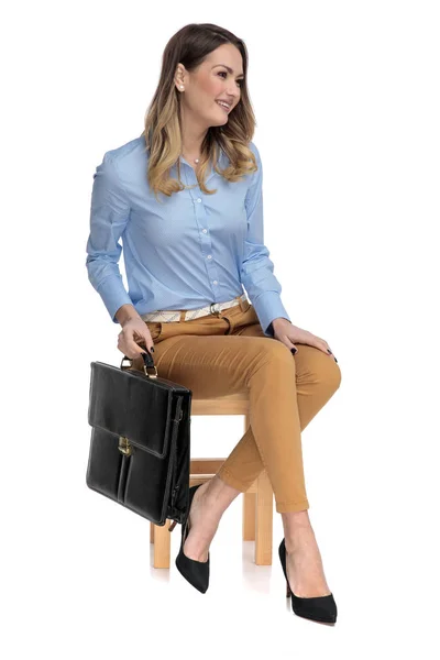 Chytrá neformální žena drží její kufr zatímco sedí na hru — Stock fotografie