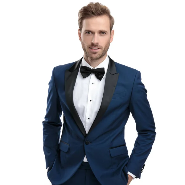 Элегантный мужчина в синем костюме, стоящий с руками в карманах — стоковое фото