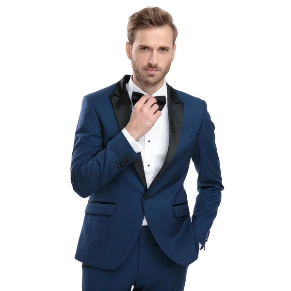 Модный парень регулирует галстук, стоя с рукой в кармане — стоковое фото