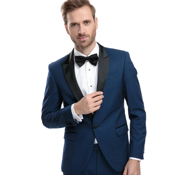 Luxe man in blauwe tuxedo aanpassen zijn kraag van de jas lounge — Stockfoto