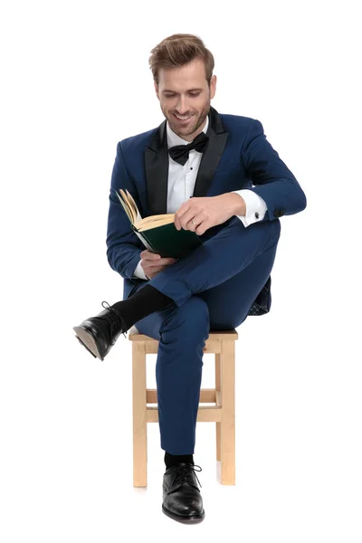 Atraktivní muž s knihou v sedle s nohama přes — Stock fotografie