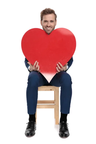 Sitzender Modemann hält ein großes rotes Herz in den Händen — Stockfoto