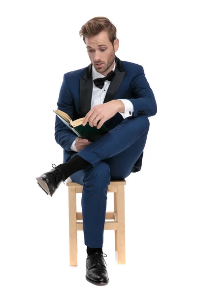 Sitzender gebannter Mann liest ein Buch mit gekreuzten Beinen — Stockfoto