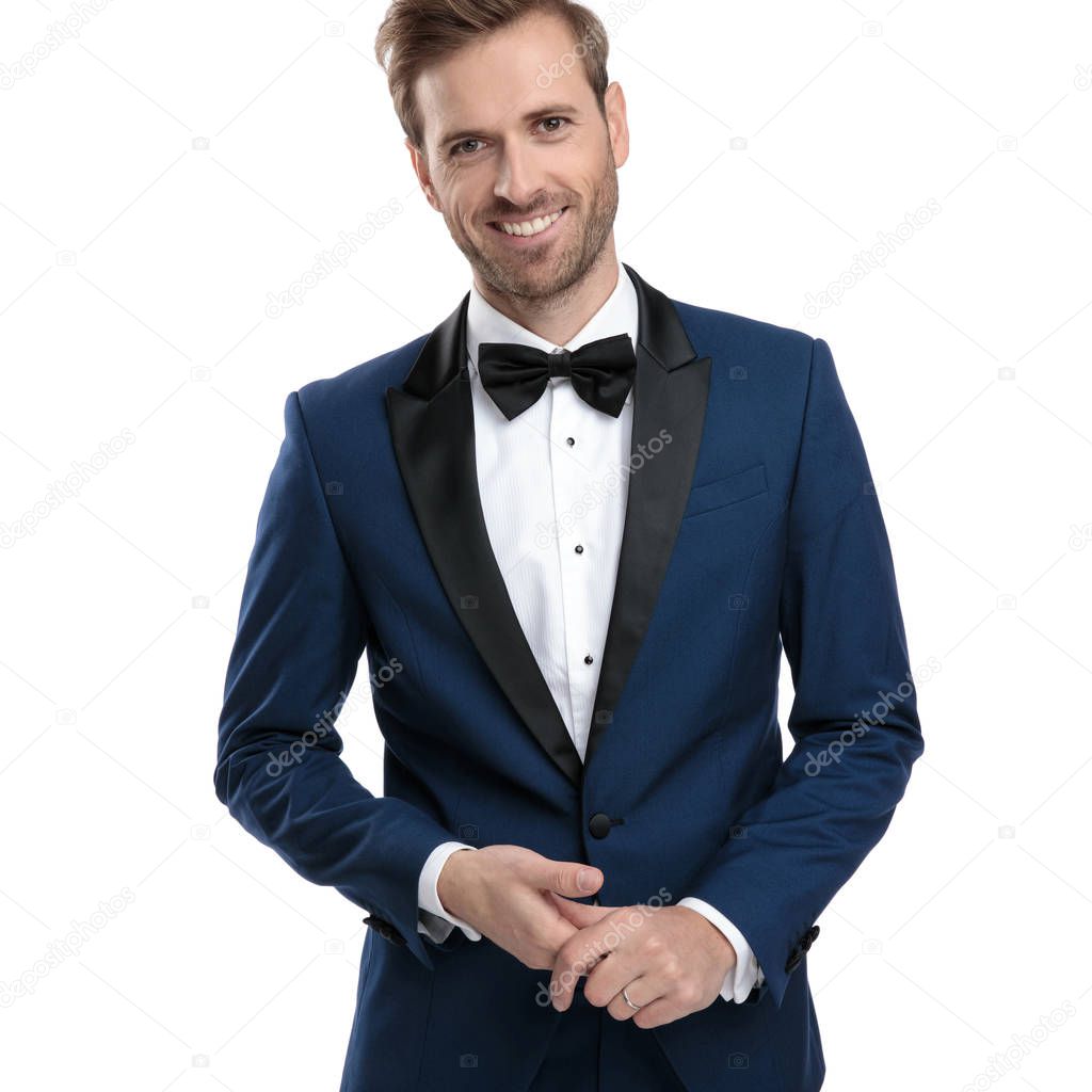 handsome man in blue tuxedo is holding his hands together