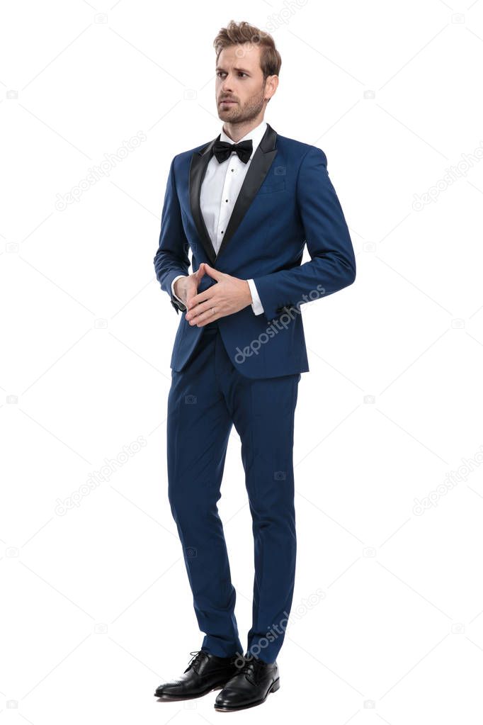 worried man in blue tuxedo standing with hands together