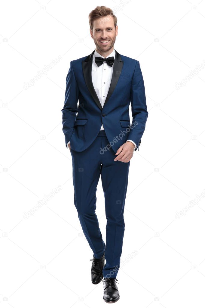 happy man in blue tuxedo walking with hand in pocket