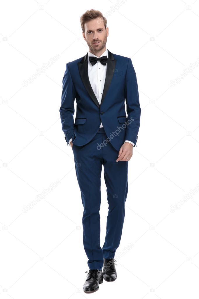 groom guy in blue tuxedo walking with hand in pocket