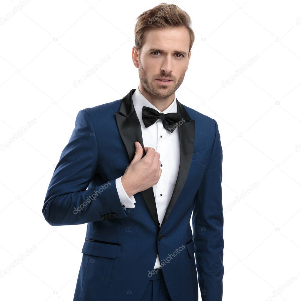 handsome guy in blue tuxedo adjusting his lounge jacket collar 