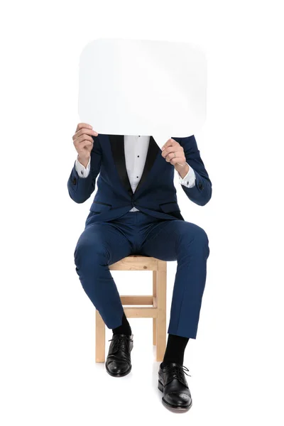 Seated stylish man covering his face with a talk bubble — Stock Photo, Image