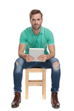 oturan çekici adam elinde bir tablet tutar