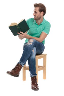 oturmuş modern adam elinde bir kitap ile uzağa bakar