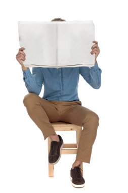 bir gazete ile yüzünü kaplayan çekici adam oturmuş