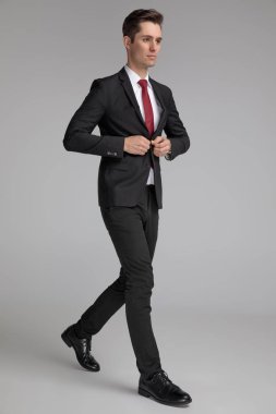 latin adam yürürken ve uzağa bakarken siyah takım elbise düğmeleme
