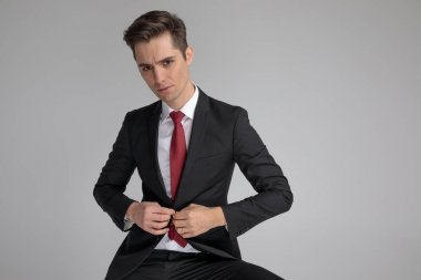 otururken onun salon ceketi düğmeleme takım elbiseli akıllı adam