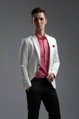 Takım elbiseli genç adam ceketini düzeltiyor.