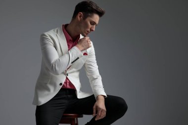 bacak üzerine kolunu dinlendirirken düşünme oturan çekici adam 