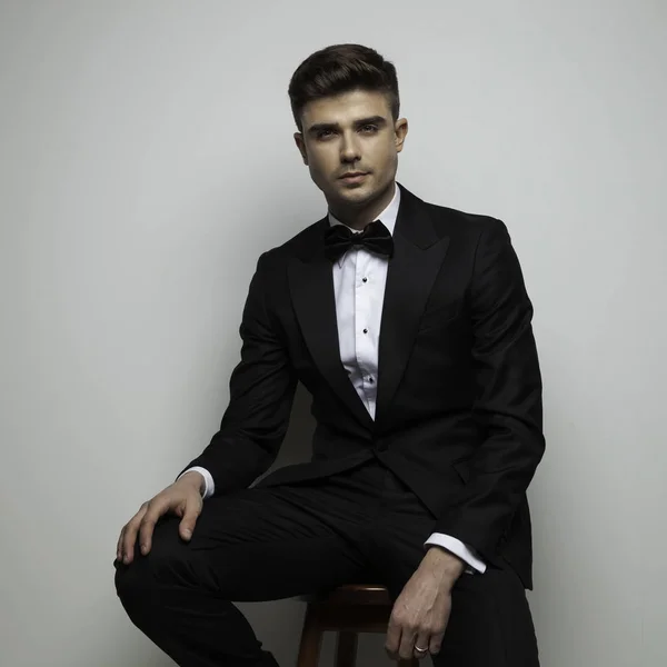 Attractive man in black tuxedo standing on chair — Stock Photo, Image