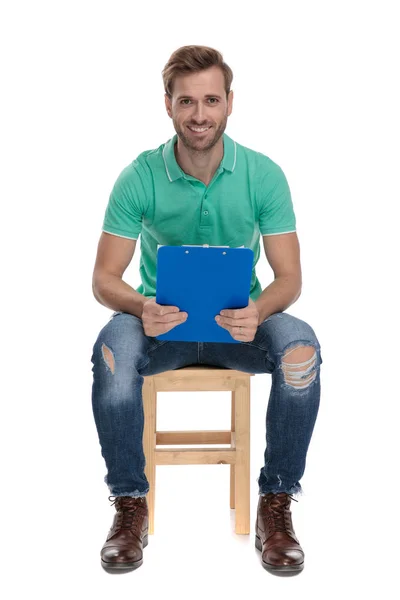 Hombre sentado sosteniendo un portapapeles en las manos —  Fotos de Stock