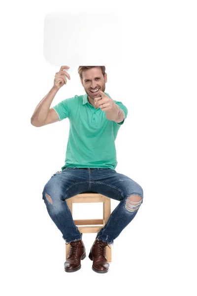 Seduto felice uomo tiene un tabellone bianco parlare su — Foto Stock