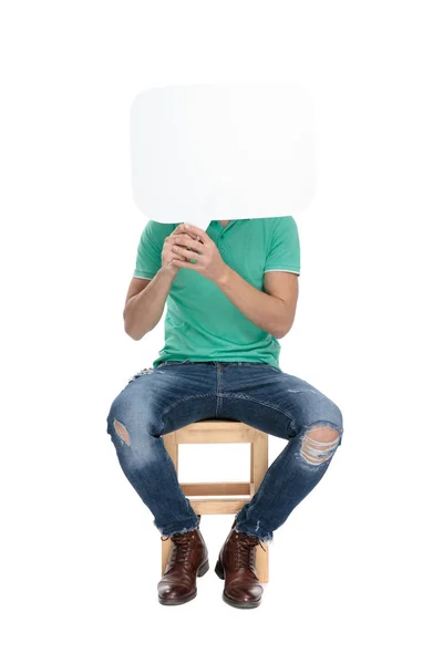 Sedící moderní muž zakrývá jeho tvář prázdnou bublinou na chatu — Stock fotografie
