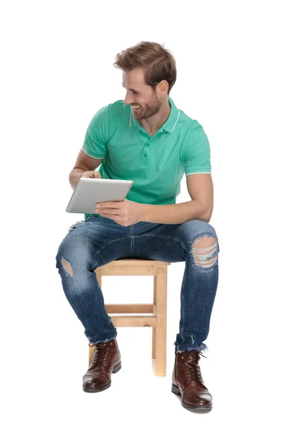 Zijaanzicht van zittende sexy man presenteert zijn Tablet — Stockfoto