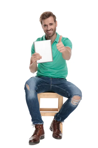 Hombre moderno sentado mostrando buen gesto con la tableta en la mano —  Fotos de Stock