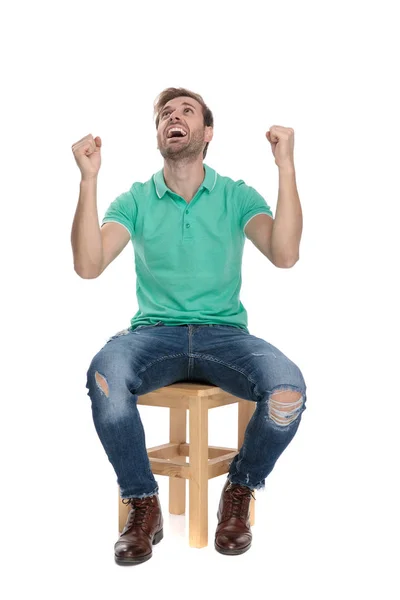 Сидящий молодой человек кричит с поднятыми руками — стоковое фото