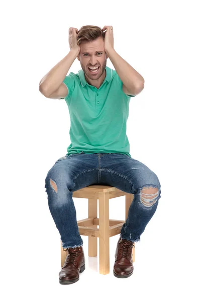 Καθισμένος αναστατωμένος άνθρωπος φωνάζει με τα χέρια στο κεφάλι — Φωτογραφία Αρχείου