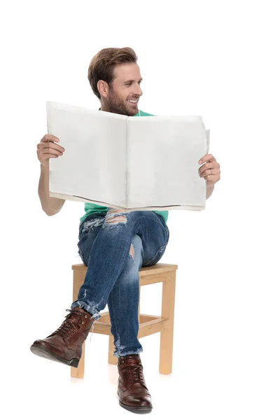 Elinde gazete ile uzağa bakarak oturmuş serin adam — Stok fotoğraf