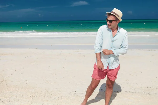 Casual man walks on the the beach and pulls  sleeve — Stock Photo, Image