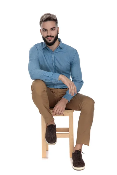 Modern man sitting relaxed with arms on legs — Stock Photo, Image