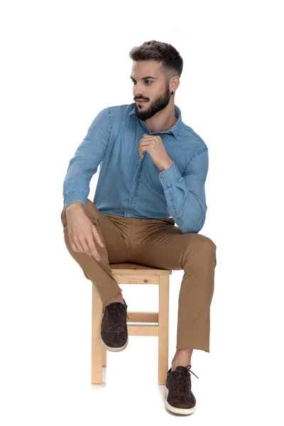 Relaxed man sitting with elbow on leg while looking away — Stock Photo, Image