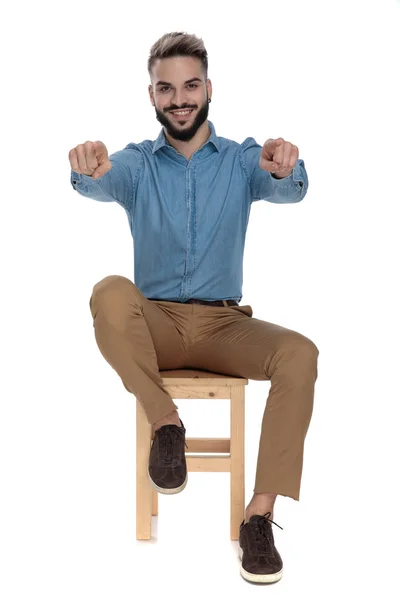 Καθισμένος ευτυχισμένος άνθρωπος δείχνοντας στην κάμερα με τα δύο χέρια — Φωτογραφία Αρχείου