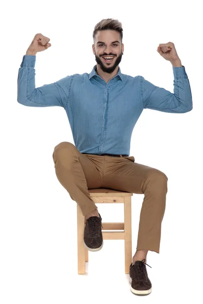 Model man sitting with fists in the air showing muscles — Stock Photo, Image